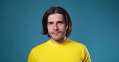 Mavi arka planda poz veren yakışıklı adam.