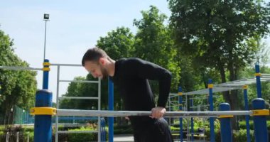Sporcu parktaki paralel çubuklara triseps daldırıyor.