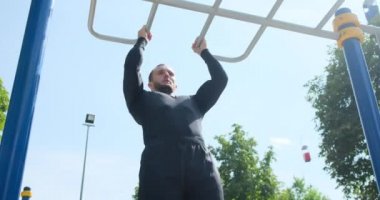 Sporcu parkta barfiks egzersizi yapıyor.
