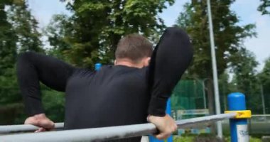 Sporcu parktaki paralel çubuklara triseps daldırıyor.