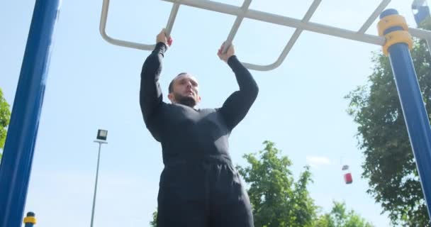 Sportman doet pull-ups oefening in het park — Stockvideo