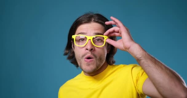 Homme aux lunettes jaunes dansant sur fond bleu — Video