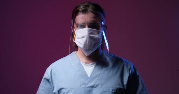 Trabajador médico con protector facial y máscara bajo luz de emergencia parpadeante — Vídeos de Stock