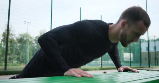 Sportsman gör push up motion på parkbänk — Stockvideo