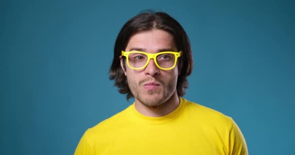 Homem de óculos amarelos dançando sobre fundo azul — Vídeo de Stock