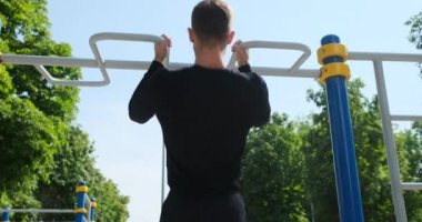 Sporcu parkta barfiks egzersizi yapıyor.