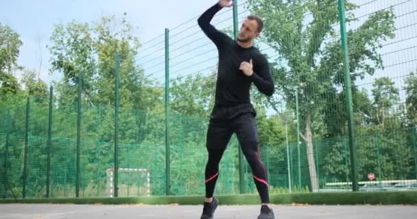 Sportman doet jump squats en stretching oefening — Stockvideo