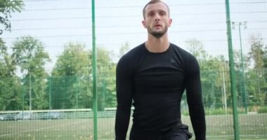 Sporcu spor sahasında esneme egzersizi yapıyor.