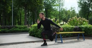 Sporcu parkta tek bacak egzersizi yapıyor.