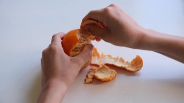 Kapalı bir masada taze portakalı elle soyan genç bir çocuğun yakın görüntüsü..