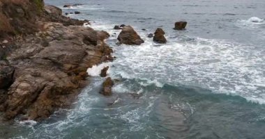 Kıyı şeridinin yüksek açılı manzarası köpüklü dalgaların engebeli bir kıyı şeridine çarpıyor..