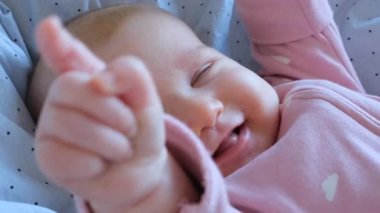 Yumuşak bir battaniyenin üzerinde uzanan bir bebeğin yavaş çekimde gülüşünü..