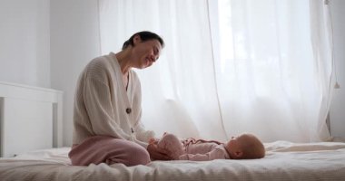 Bir anne, yavrusu için yumuşak bir bacak egzersizi ve hareket kabiliyeti uygular..