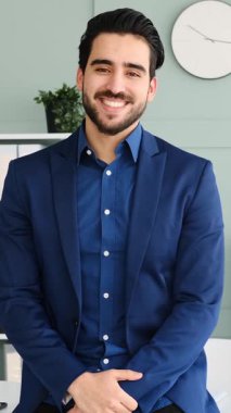 Yetişkin adam modern bir ofis ortamında dizüstü bilgisayar ve belgelerle yumuşak doğal ışık altında çalışır. Yavaş çekimde yakalanır..