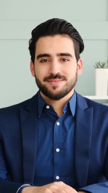 Yetişkin adam modern bir ofis ortamında dizüstü bilgisayar ve belgelerle yumuşak doğal ışık altında çalışır. Yavaş çekimde yakalanır..