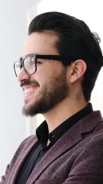 Yetişkin adam modern bir ofis ortamında dizüstü bilgisayar ve belgelerle yumuşak doğal ışık altında çalışır. Yavaş çekimde yakalanır..