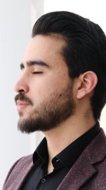 Yetişkin adam modern bir ofis ortamında dizüstü bilgisayar ve belgelerle yumuşak doğal ışık altında çalışır. Yavaş çekimde yakalanır..