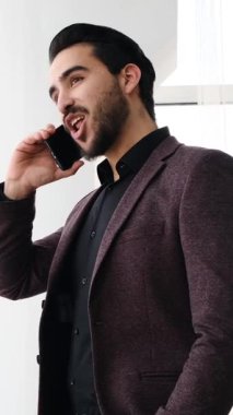 Yetişkin adam modern bir ofis ortamında dizüstü bilgisayar ve belgelerle yumuşak doğal ışık altında çalışır. Yavaş çekimde yakalanır..