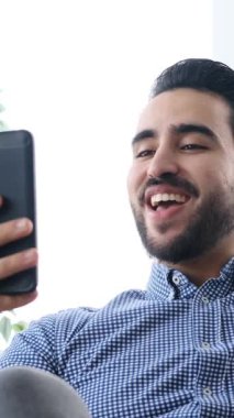 Yetişkin bir adam evdeki kanepeye yaslanır, gözleri kapalı ve gülümserken kulaklıkla kulaklıkla müzik dinler, yavaş çekimde yakalanır..