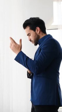 Yetişkin adam modern bir ofis ortamında dizüstü bilgisayar ve belgelerle yumuşak doğal ışık altında çalışır. Yavaş çekimde yakalanır..