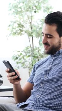 Yetişkin bir adam evdeki kanepeye yaslanır, gözleri kapalı ve gülümserken kulaklıkla kulaklıkla müzik dinler, yavaş çekimde yakalanır..