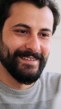 Modern, parlak bir ofiste dizüstü bilgisayarda çalışırken gülümseyen yetişkin bir adamın yakın çekimi..