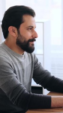 Modern, parlak bir ofiste dizüstü bilgisayara gülümseyen yetişkin bir adamın yan görüntüsü..