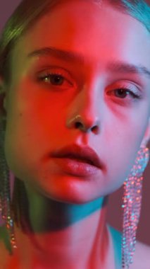 Genç bir kadının kırmızı ve yeşil jel ışıklandırmalı aşırı yakın çekimi parlak gölgeler ve yavaş çekimde çekilen gölgeler yaratır..