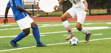 Bir lise socceer oyuncu topa bir oyun sırasında onun coompetitor etrafında bir hareket yapmaya hazır getting adım.