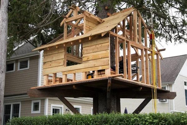 A tree house is under construction in a families backyard for their children to play in.