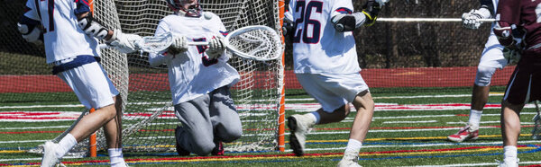 High school boys lacrosse golie blocks a shot during a game.