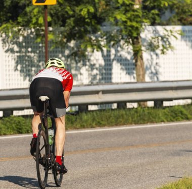 Uzak yollarda kamera eğitim güneşli yaz sabahı ridding bir bisikletçi.