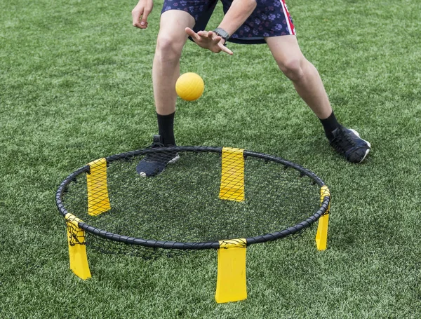 A player is playing spike ball on a green turf field.