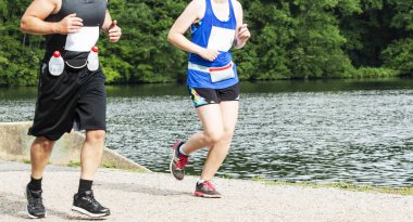 Bir adam ve bir kadın yan yana bir göl bir toprak yolda geçen ormanda çalışan.