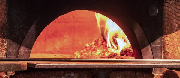 A wood fired brick oven is hot and ready to make pizza at an italian resturant.
