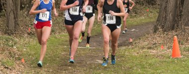 Bir çapraz ülke yarış bir toprak yol oklar ve yol işaretleme koniler ile çalışan liseli kızlar.