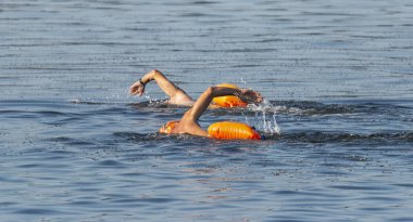 İki erkek yüzücüler, arkalarında güvenliği için yüzen oange flotasyon cihazlar ile Long Island Sound açık havada yüzüyor.