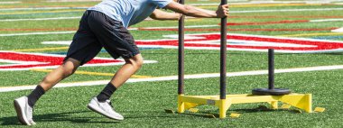 Lise çapraz ülke runner ağırlığı ile sarı bir kızak üzerinde preseason kuvvet ve çeviklik antrenman sırasında bastırıyor.