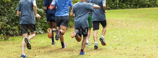 Grupo de corredores do ensino médio treinando em um parque — Fotografia de Stock