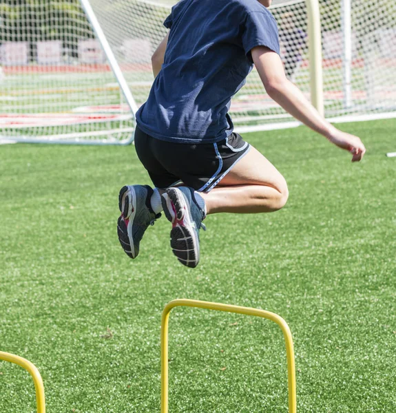 Atleet over twee voet hoge gele hindernis springen — Stockfoto