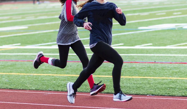 Duas adolescentes correndo rápido em uma pista — Fotografia de Stock