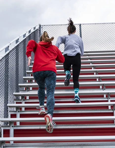 Duas mulheres atletas do ensino médio correndo bancadas — Fotografia de Stock