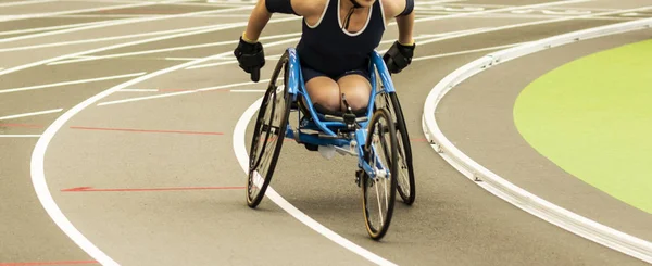 Corrida de atleta de cadeira de rodas em pista coberta — Fotografia de Stock