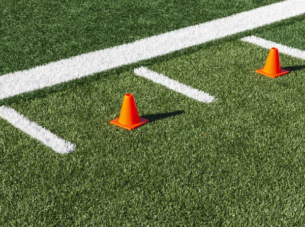 Dos conos naranja entre marcas de hachís en el campo de fútbol —  Fotos de Stock