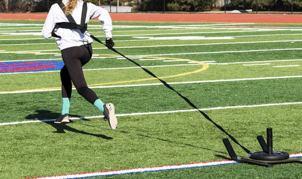 Behind view of girl pulling weighted sled — Stockfoto