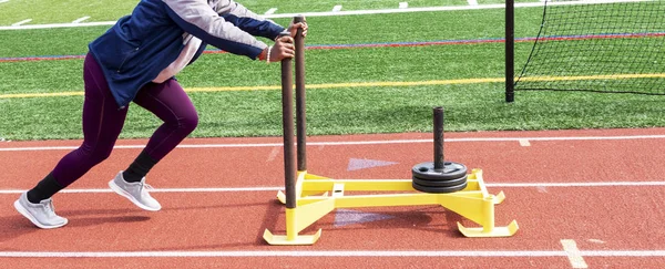 High school girl pushing sled with 75 pounds. — Stock Photo, Image