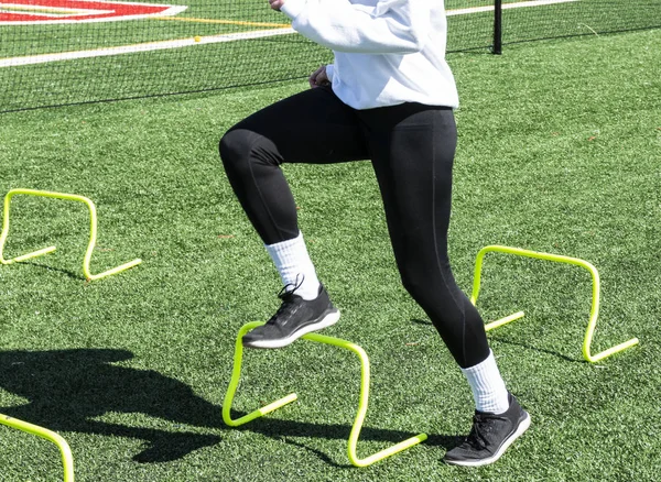 Atleta femminile che supera i mini ostacoli gialli — Foto Stock