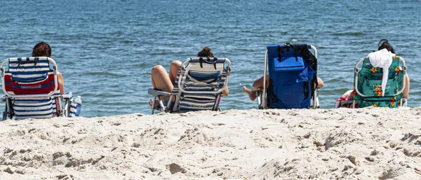 Čtyři přátelé v plážových křeslech u oceánu — Stock fotografie