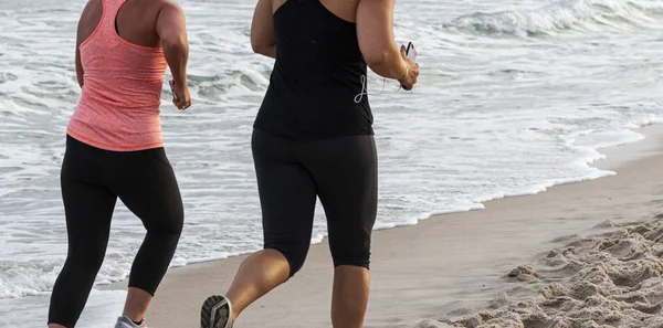 Duas mulheres correndo ao longo da costa na praia — Fotografia de Stock