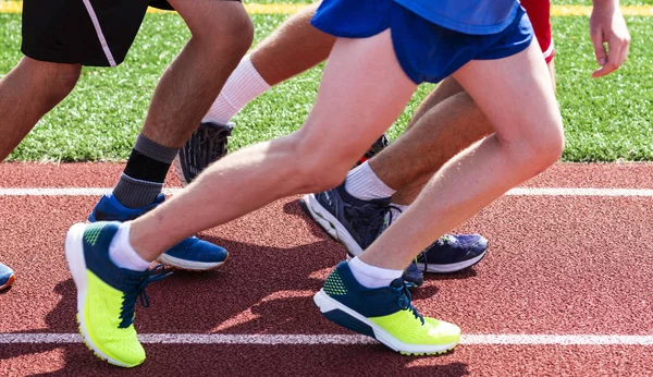 Pernas de um grupo de corredores na pista prontos para iniciar uma corrida — Fotografia de Stock